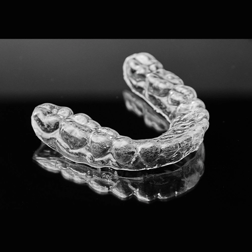 Transparent dental retainers on a black reflective surface used for maintaining teeth alignment after orthodontic treatment.