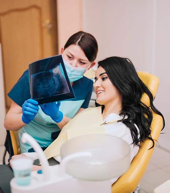 Dentist showing dental X-ray to a patient during consultation at dental clinic.