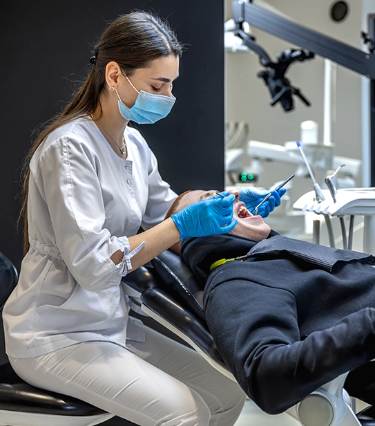 Female dentist treating a patient and performing a dental filling procedure using professional dental equipment