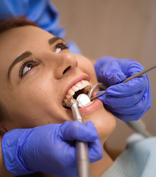 Dentist using dental tools to examine a patient’s tooth with a loose or missing crown in a dental clinic.