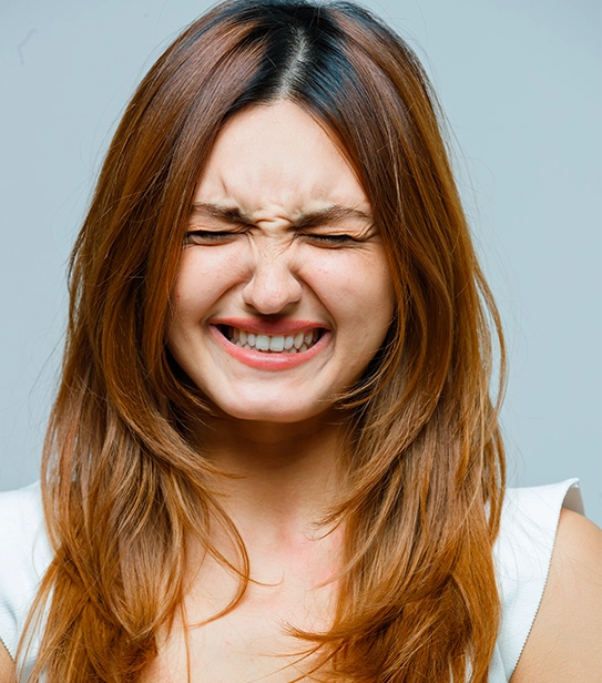 Woman experiencing tooth pain due to broken veneer