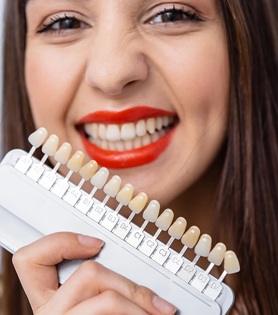 Woman comparing dental shades for veneer replacement after broken veneer
