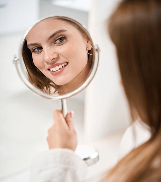 Close-up of a patient admiring her smile results in a mirror after a professional dental cleaning.