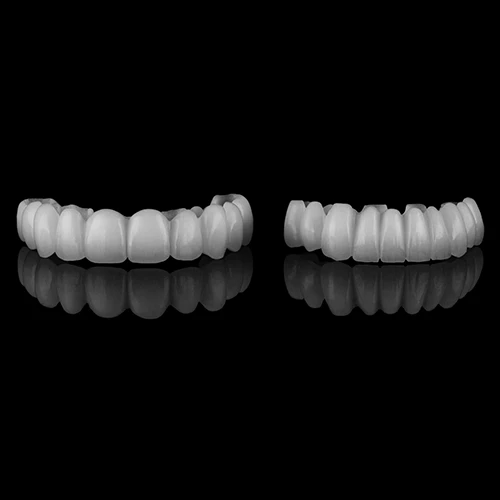A professional studio shot of two full-arch dental prosthetics on a black reflective surface, showcasing high-quality aesthetic tooth replacement.