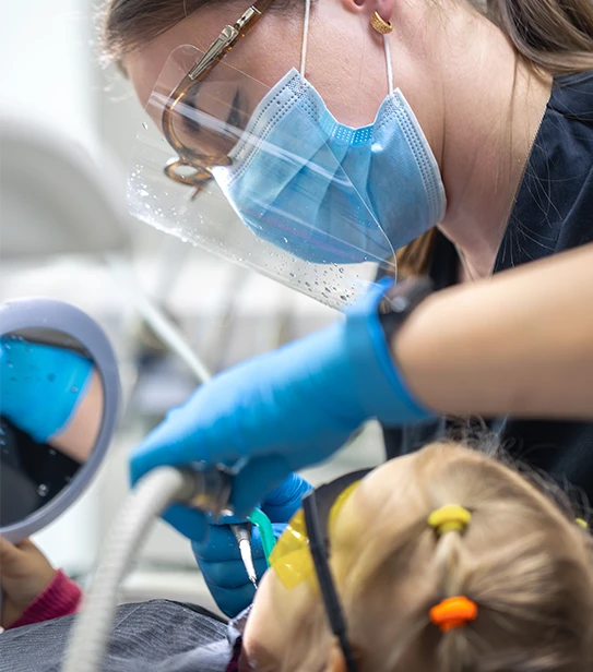 Professional pediatric dentist providing gentle tooth treatment and oral care for children in a specialized dental clinic.