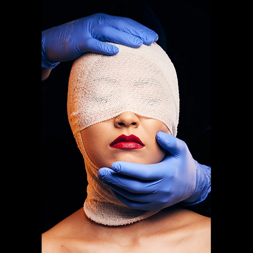 Woman with face bandaged after cosmetic surgery, doctor examining facial recovery