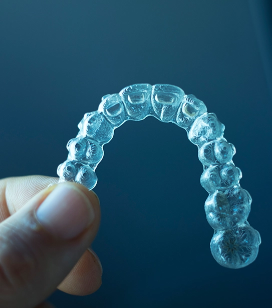 Hand holding clear TMJ splint dental appliance used for jaw alignment and TMJ disorder treatment